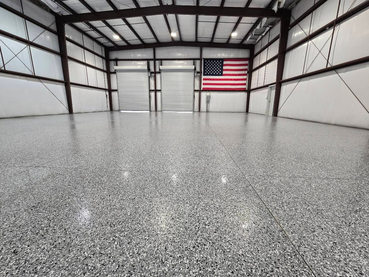 Finished flake concrete coating across a workshop floor beneath an American flag.